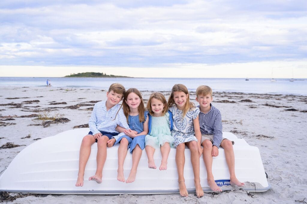 kids sitting on a boat at goose rocks beach in kennebunkport maine for their sunset family portraits