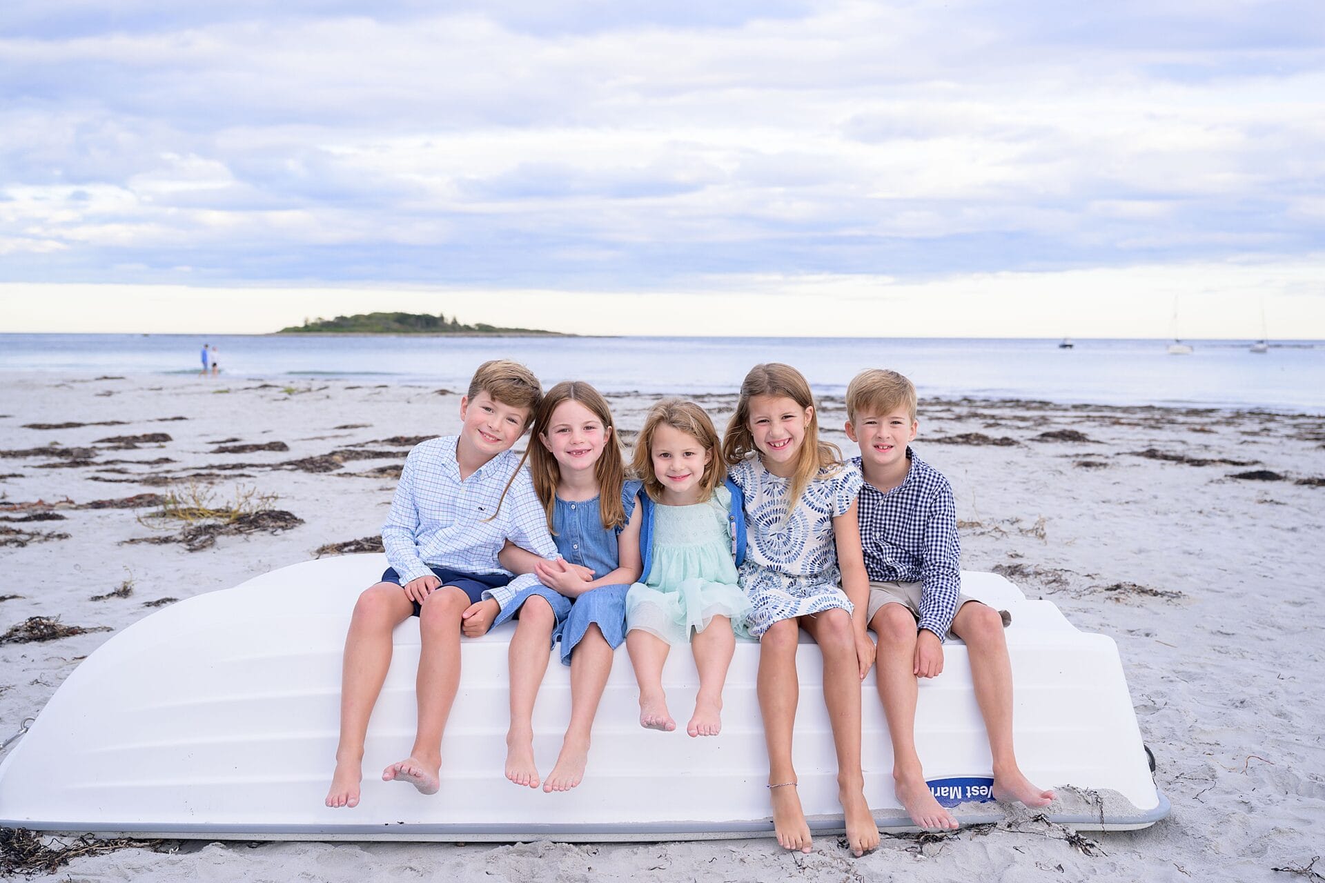 kids sitting on a boat at goose rocks beach in kennebunkport maine for their sunset family portraits